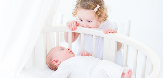 petite fille regarde bébé dans le lit